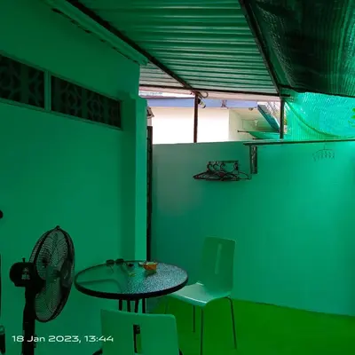a green room with a table and a chair at Cheras Homestay Family room with Private Bathroom in Kuala Lumpur
