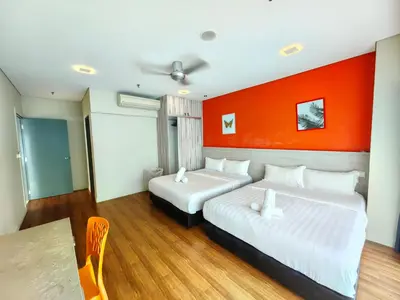 two beds in a hotel room with an orange wall at Summer Suites by Moon Orchid in Kuala Lumpur