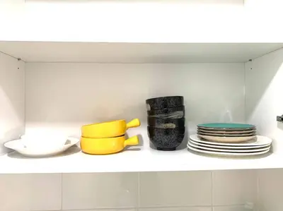 a kitchen shelf with plates and cups and plates at MITEC Publika 500Mbp Wi-fi Studio Mont Kiara Hartamas in Kuala Lumpur