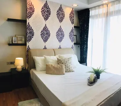 a bedroom with a large bed with white sheets and a wall at Kuala Lumpur Bukit Bintang LaLaport Serviced Suite KLCC in Kuala Lumpur