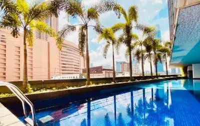 a swimming pool with palm trees on a building at Kuala Lumpur Bukit Bintang LaLaport Serviced Suite KLCC in Kuala Lumpur