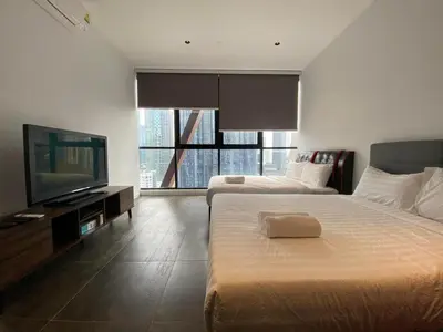 a bedroom with two beds and a flat screen tv at Infini Suites@ Scarletz Suites KLCC in Kuala Lumpur