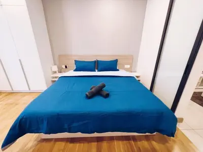 a bed with a blue blanket and a brown object on it at [Promo] Connected Train 2 Bedroom (ABOVE MALL) 28 in Kuala Lumpur