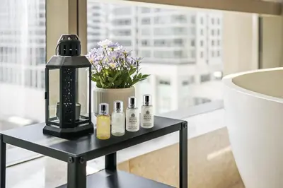 a black table with five bottles on it with a vase of flowers at Atelier Bukit Bintang in Kuala Lumpur