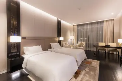 two beds in a hotel room with a desk and a table at Atelier Bukit Bintang in Kuala Lumpur