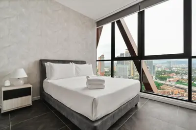 a bedroom with a bed with white sheets and windows at Scarletz KLCC Apartments by soulasia in Kuala Lumpur