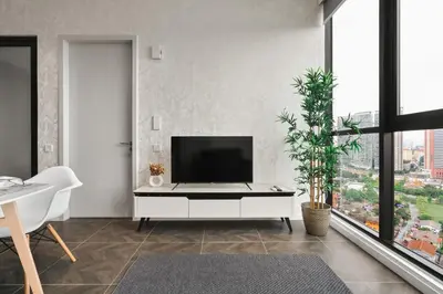 a living room with a tv on a white cabinet at Scarletz KLCC Apartments by soulasia in Kuala Lumpur