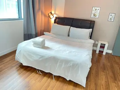 a bedroom with a large white bed with a wooden floor at Mercu Summer Suite KLCC by Minshuku in Kuala Lumpur