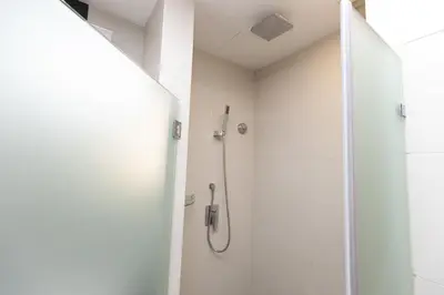 a shower in a white bathroom with a glass door at Dua Sentral Residence near KL Sentral by COBNB in Kuala Lumpur