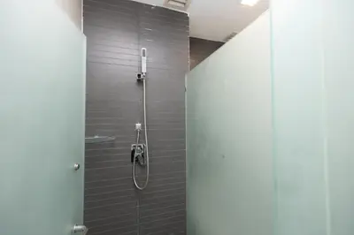 a bathroom with a shower with black tiles at Dua Sentral Residence near KL Sentral by COBNB in Kuala Lumpur