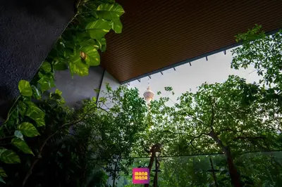 a building with a pink sign in front of trees at Ceylonz KLCC by Mana-Mana in Kuala Lumpur