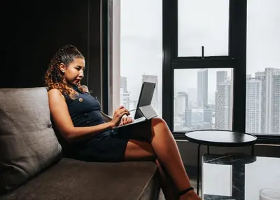 a woman sitting on a couch with a laptop at Ceylonz KLCC by Mana-Mana in Kuala Lumpur