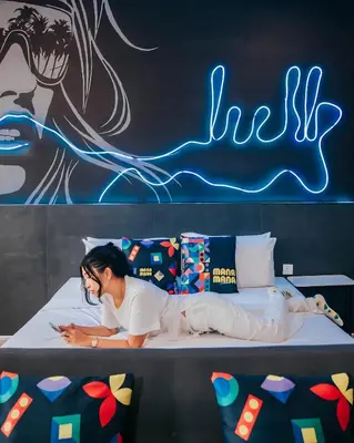 a woman laying on a bed with a skateboard at Ceylonz KLCC by Mana-Mana in Kuala Lumpur