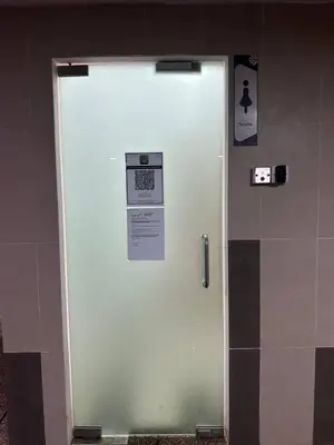 a glass shower door in a public bathroom at KLCC Kampung Baru Cottage - Homestay in Kuala Lumpur