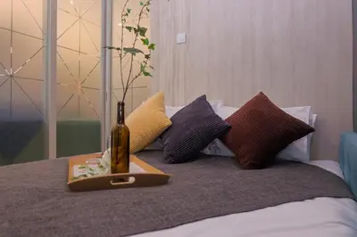 a bottle of wine sitting on a bed with pillows at S27- Bukit Bintang Robertson 3BR Suite with Netflix in Kuala Lumpur