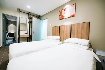 two beds in a hotel room with white sheets at Chill Suites Kuala Lumpur in Kuala Lumpur