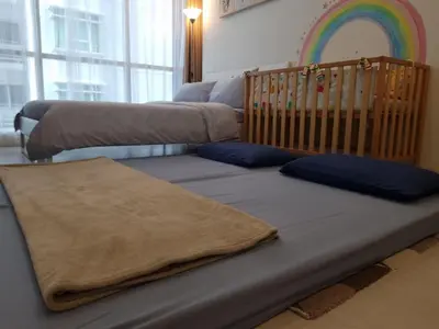 a bed with a blanket and a crib with a rainbow at Kuala Lumpur Kids Friendly Playground Bunk Bed in Kuala Lumpur