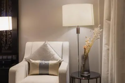 a white chair with a pillow next to a lamp at Bukit Bintang Signatures Pavilion Kuala Lumpur in Kuala Lumpur