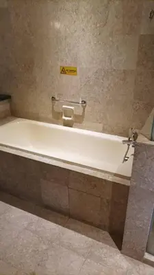 a bath tub in a bathroom with a sign on the wall at TM SUITE at BERJAYA TIME SQUARE KL in Kuala Lumpur
