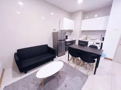a kitchen with a black couch and a table and chairs at [PROMO]Connected train 1 Bedroom (ABOVE MALL)6 in Kuala Lumpur