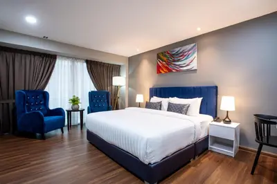 a bedroom with a bed and two blue chairs at Raissa Boutique Hotel in Kuala Lumpur