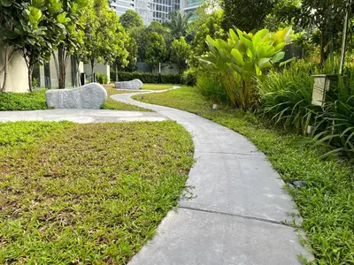 a path in a park with a bench on the grass at EatonResidences KLCC by MAH in Kuala Lumpur