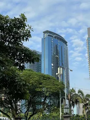 a tall blue building with trees in front of it at EatonResidences KLCC by MAH in Kuala Lumpur