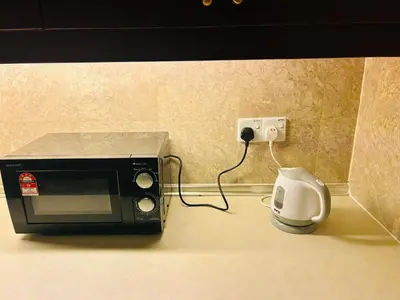 a microwave sitting on a counter next to an outlet at TWO BEDROOM SUITES at TIMES SQUARE KL in Kuala Lumpur