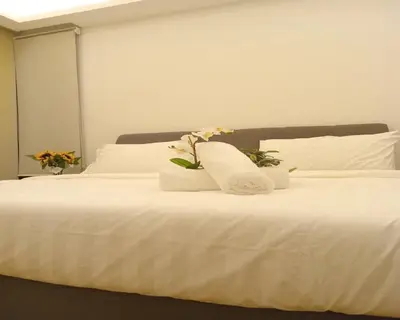 a white bed with two pillows and flowers on it at Suasana Suites KLCC by Grand Royal in Kuala Lumpur