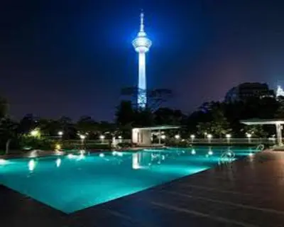 a swimming pool with a tower in the background at night at Suasana Suites KLCC by Grand Royal in Kuala Lumpur