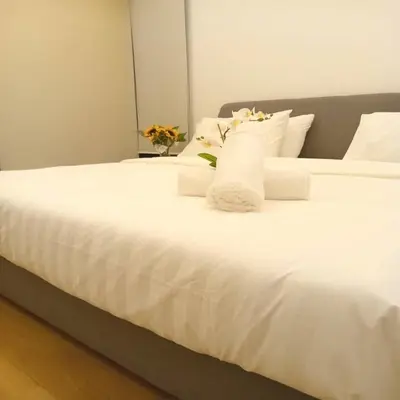 a white bed with white pillows and flowers on it at Suasana Suites KLCC by Grand Royal in Kuala Lumpur