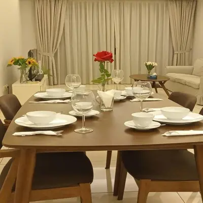 a wooden table with plates and wine glasses on it at Suasana Suites KLCC by Grand Royal in Kuala Lumpur