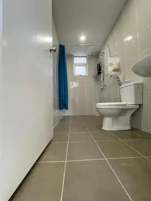 a bathroom with a toilet and a blue shower curtain at Bayu Andaman KL Centre in Kuala Lumpur