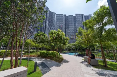 a man sitting on a bench in a park with tall buildings at M Vertica Premier Suites Kuala Lumpur in Kuala Lumpur