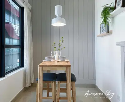 a small wooden table with two chairs and a pendant light at Arte Plus Ampang By Awesomestay in Kuala Lumpur