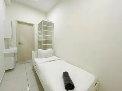 a white bed with a black object on it in a room at Arte Mont Kiara By The Relaxstay in Kuala Lumpur