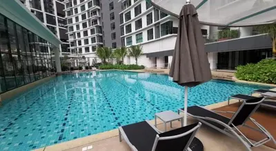 a large swimming pool with chairs and an umbrella at OOAK residence in Kuala Lumpur