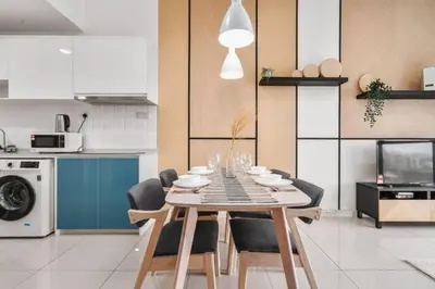 a dining room table with chairs and a kitchen at Cozy Studio near TRX By Rumabnb in Kuala Lumpur