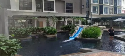 a woman standing next to a water slide in a building at Cozy Apartment with Jacuzzi and Sauna at 188 Suites Klcc in Kuala Lumpur