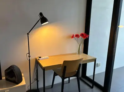 a desk with a lamp and a vase with red flowers at KLSentral-Bangsar-MidValley-2-10pax-Netflix-Balcony-Super Fast Internet in Kuala Lumpur
